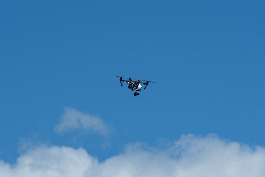 Drone flying against blue sky with white clouds below