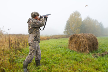 a hunter shoots at a flying bird