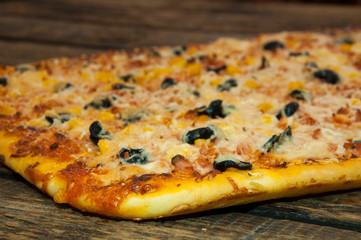 Homemade pizza. Cheese and olives. On a wooden background.