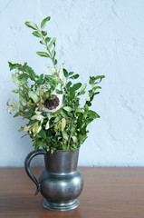 Vintage vase with green plants flowers. Boxwood. against the background of the wall. On wooden background