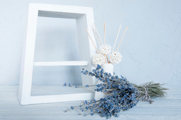 Blue flowers on the table. White frame. Wood background. Vase with aromatic sticks. Still life