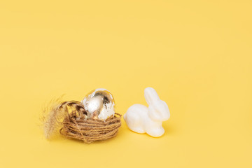 Golden chocolate Easter eggs and chocolate bunny with copy space on a yellow background