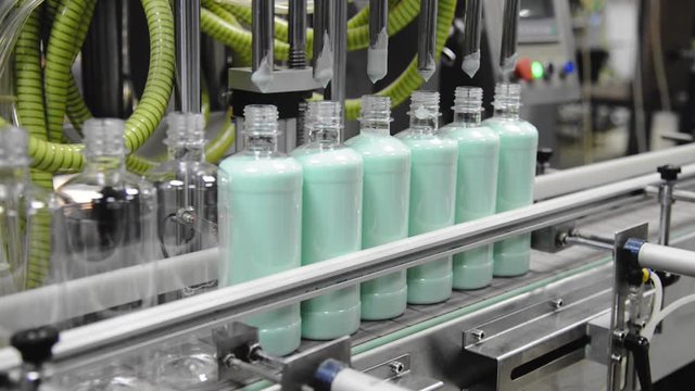 Conveyor of the production line with filling of transparent plastic bottles at the factory