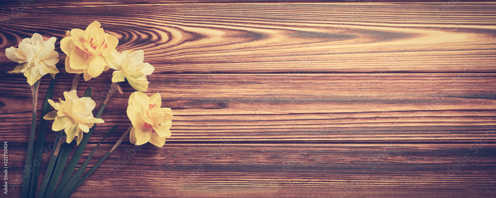 Poster bouquet of yellow daffodils on a wooden background with copy space web banner: spring time concept