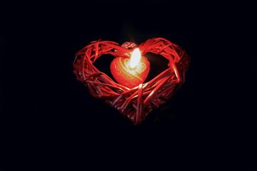 Burning red heart-shaped candle in the dark