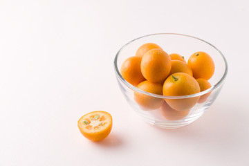tropical kumquat fruit in a glass bowl on a white background. copy space