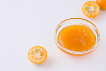 kumquat tropical citrus fruit jam on white plate next to fresh ingredients