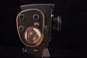 Photograph of an old 8mm movie camera under artificial lighting on a black background. Retro camera...