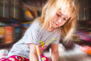 Cute small girl with long blond hair is drawing. Child evolution concept. Focus on foreground and close up. 