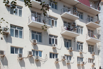 The facade of the building with a white wall, air conditioning, the same windows in the summer resort town.