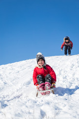 Children have fun sledding on a sunny day