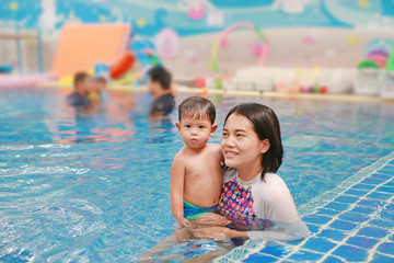 Obraz premium Asian Mother and baby boy relaxing in swimming pool training.