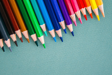 flat lay on the theme of drawing and creativity: color pencils on a green background, place for text 