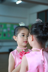 Cute little Asian ballerina girl in a pink tutu posing with mirror reflection.