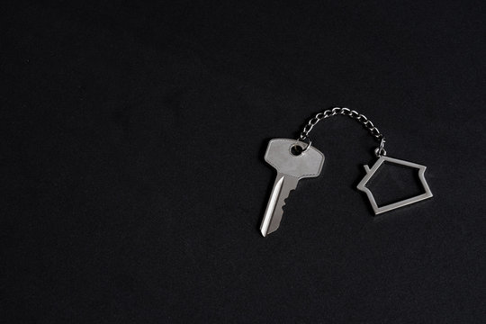 Home key with house keychain on black background