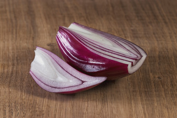 Red onion is cut in half and lies on a white oak kitchen board, with artificial lighting. Still life for the kitchen or element of the vegetarian menu.
