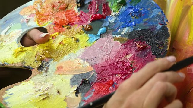 artist girl paints on canvas and mix with paint on palette