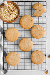 Freshly baked oatmeal raisin cookies on cooling rack on a light stone background. Closeup from above with natural directional lighting. Vertical orientation.