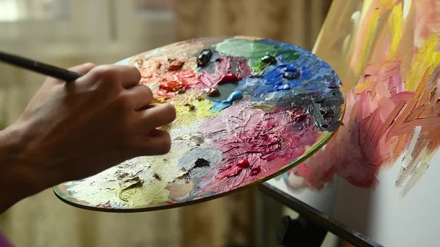 artist girl paints on canvas and mix with paint on palette