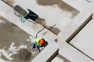 Uniformed workers clean sand on a construction site, top view.