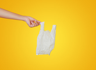 Close up people hand holding a white thin polythene plastic bag isolated on yellow background.