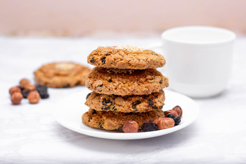 Fresh oatmeal friable cookies on a plate with nuts and raisins. The concept of a delicious and healthy breakfast.