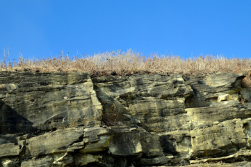 Two colors of blue sky and light brown crag with dry grass