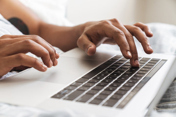 Guy in the morning in bedroom using laptop computer