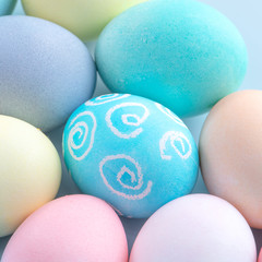 Colorful Easter eggs dyed by colored water isolated on a pale blue background, design concept of Easter holiday activity, close up, copy space.