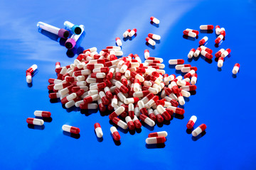 pile of medical capsules on a blue shining background