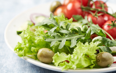 Healthy salad with green olives, cherry tomatoes and rocket. Close up.	