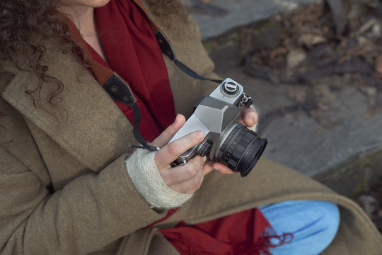 Curly haired photographer woman holding her camera in the park and shooting