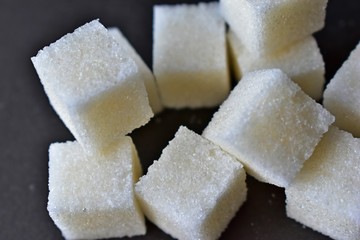 Square pieces of refined sugar on a black background