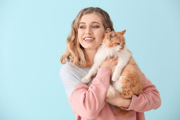 Fototapeta na wymiar Beautiful young woman with cute cat on color background