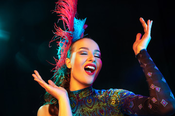 Delight. Beautiful young woman in carnival, stylish masquerade costume with feathers on black...