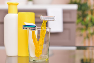 Razors for hair removal with cosmetics on table in bathroom