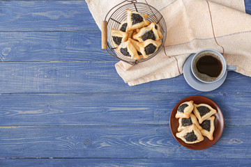 Tasty hamantaschen for Purim holiday and cup of coffee on table