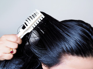 Close-up on head of Asian people have long black hair, combing hair with hairbrush. Black and thick hair health.