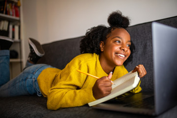happy african american girl student looking at laptop computer screen at home
