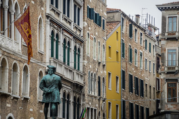 Fototapeta na wymiar Sculpture in Venice with street and colored buildings. Italy, Europe.