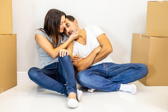 Young tired couple feeling fatigue on long hard moving out day, exhausted restless man sleeping on woman's shoulder, while they are sitting on the floor among boxes.