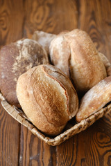 Assortment of baked bread on wooden table background. Bread background, top view of white, black and rye loaves. Healthy food. 