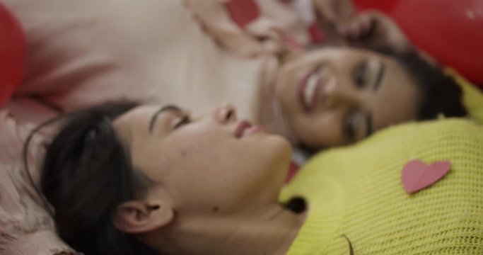 Close up CU handheld slow-motion of two young Indian lovers women lying down as they hold, embrace and kiss each other in moments of pure love and joy for their wedding honeymoon photo video shoot