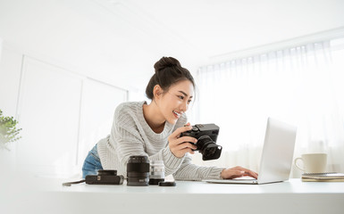 Portrait of beautiful asian photographer woman working home office holding camera with laptop. Business people employee freelance online marketing. Successful freelance creative artist girl business