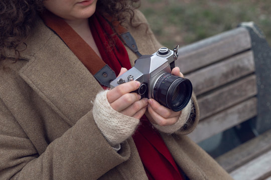 Curly haired photographer woman holding her camera in the park and shooting