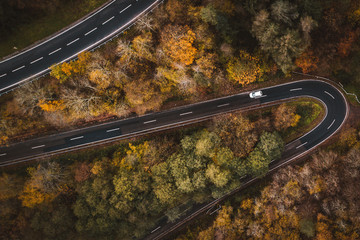 Aerial view of a road trip on a meandering road through forests during autumn in Cochem, Germany,...