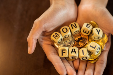 wood cube word "money" and "fail" on coin in hands.