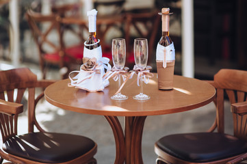 Wedding decorations for the newlyweds. Two decorated bottles, in the form of a bride and groom, glasses with ribbons stand on a wooden table. Photography, concept, composition.