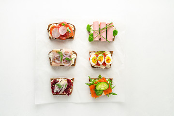 Selection of Danish smorrebrod open sandwiches on parchment paper on white background