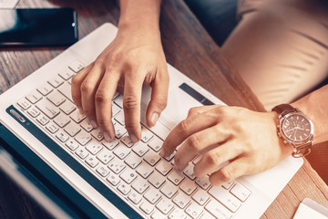 Working with laptop, hands typing on laptop keyboard at the office.